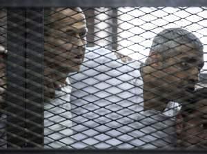 Al-Jazeera news channel's Australian journalist Peter Greste, left, and his colleagues, Egyptian-Canadian Mohamed Fadel Fahmy, center, and Egyptian Baher Mohamed listen to the verdict inside the defendants' cage during their trial for alleg