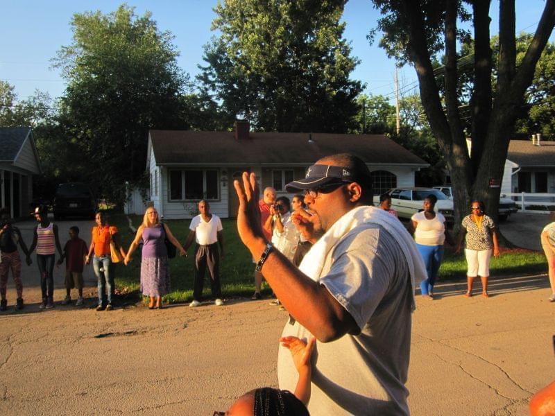 Rev. Lekevie Johnson of Jericho Missionary Baptist Church prays with about 100 participants gathered in a prayer circle during a community walk for peace in Champaign's Garden Hills neighborhood Wednesday evening.
