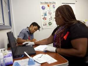 Katherine Tapp, 26, of New York City, left, fills out forms as Natrussa Williams, an HIV tester and counselor, waits for the results of Tapp's oral HIV test in southeast Washington, Wednesday, June 27, 2012.