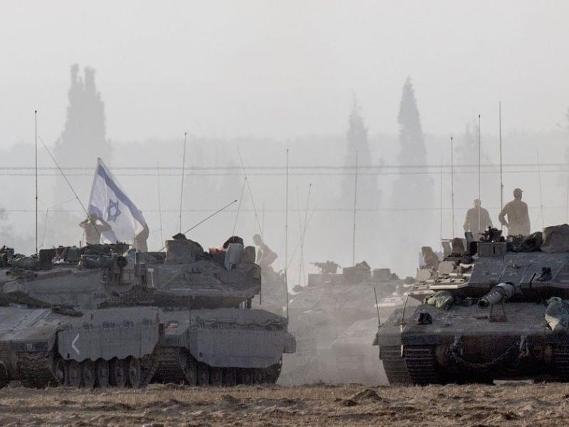 Israeli soldiers stand on their tanks near Israel's border with the Gaza Strip on Tuesday. Israeli warplanes pounded Gaza with more than 50 strikes overnight after Hamas militants fired scores of rockets over the border.