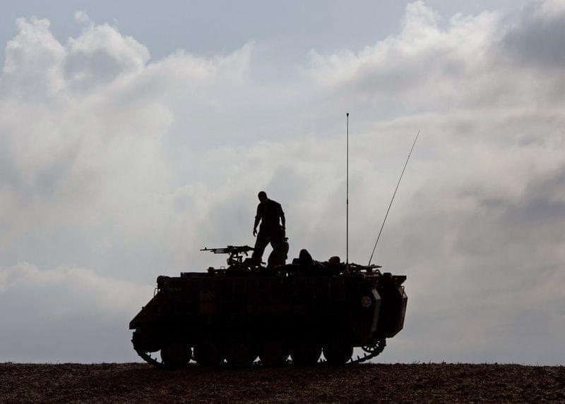 Israeli soldier stands on military vehicle near Gaza.
