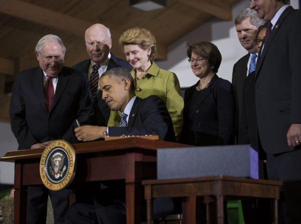Sen. Debbie Stabenow, D-Mich., (in green), watches as President Barack Obama signs the Farm Bill at Michigan State University on Feb. 7, 2014.