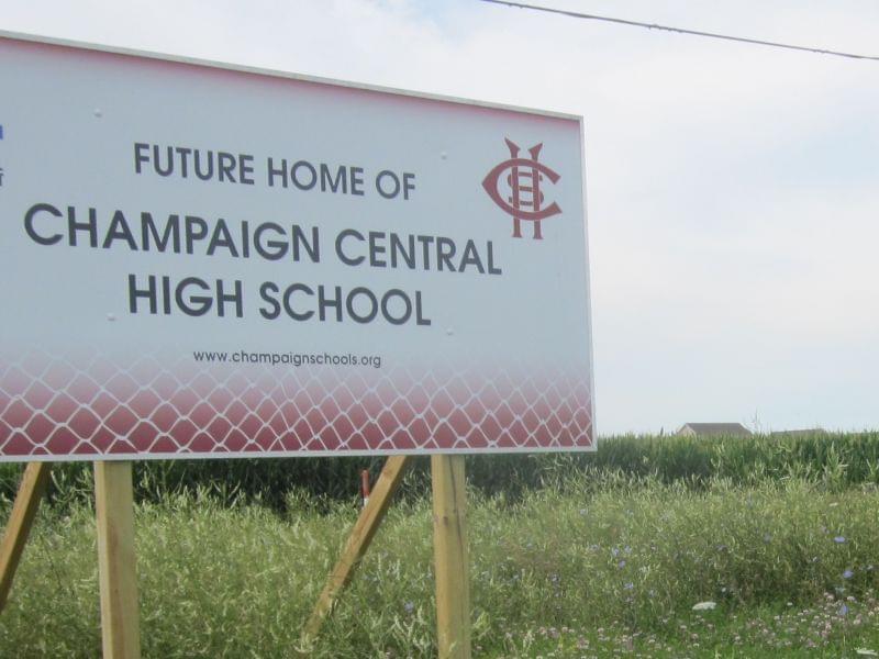 A sign announcing the site of a future Champaign Central High School stands in a field along Olympian Drive on the north edge of Champaign, with the Ashland Park residential subdivision visible in the distance.