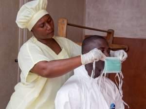 A healthcare worker, left, helps a collegue at Kenema Government Hospital.