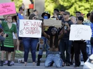 Protesters hold up signs along a road Tuesday, Aug. 12, 2014, in Ferguson, Mo. Racial tensions have run high in in the predominantly black city of Ferguson, following the shooting death by police of Michael Brown, 18, an unarmed black man.