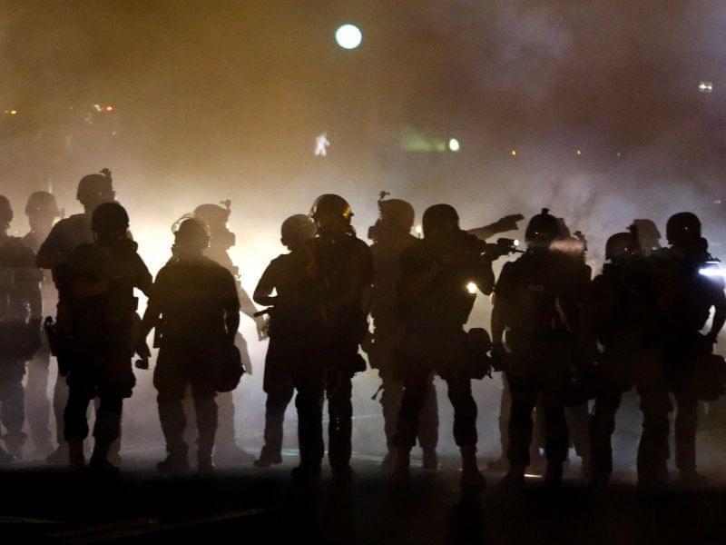 Police walk through a cloud of smoke, clashing with protesters in Ferguson, Mo. Wednesday night. 
