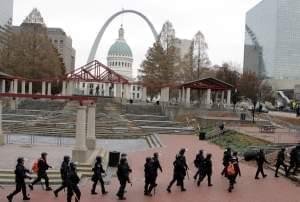 Officers wear riot gear walking through a park in downtown St. Louis. 