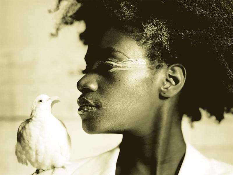 Photo of an African-American woman in profile with dove sitting on her shoulder.