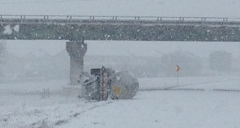 An overturned semi-tractor tanker trailer lies along I-57 in Champaign in snowy weather, following an accident.