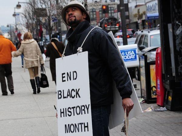 Filmmaker Shukree Tilghman wearing a protest sign in Harlem.