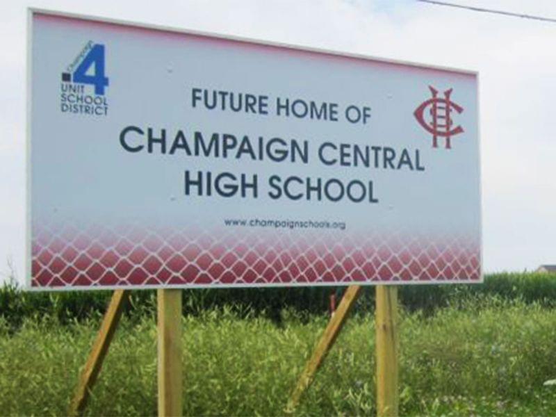 A sign at the proposed future site of Champaign Central High School stands in a field along Olympian Drive on the north edge of Champaign, with the Ashland Park residential subdivision visible in the distance.