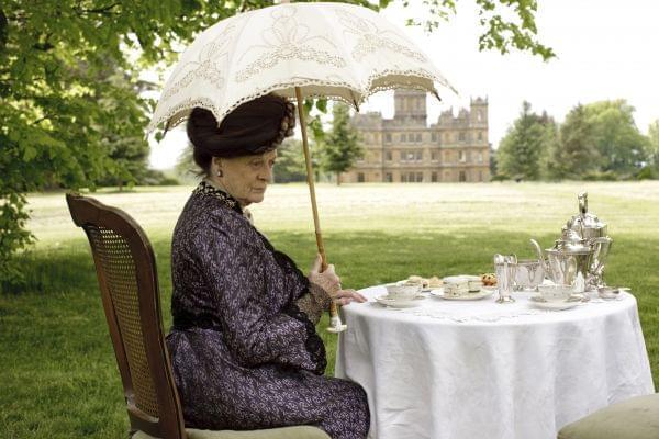 The Dowager Countess sits at a table on the lawn of Downton Abbey.