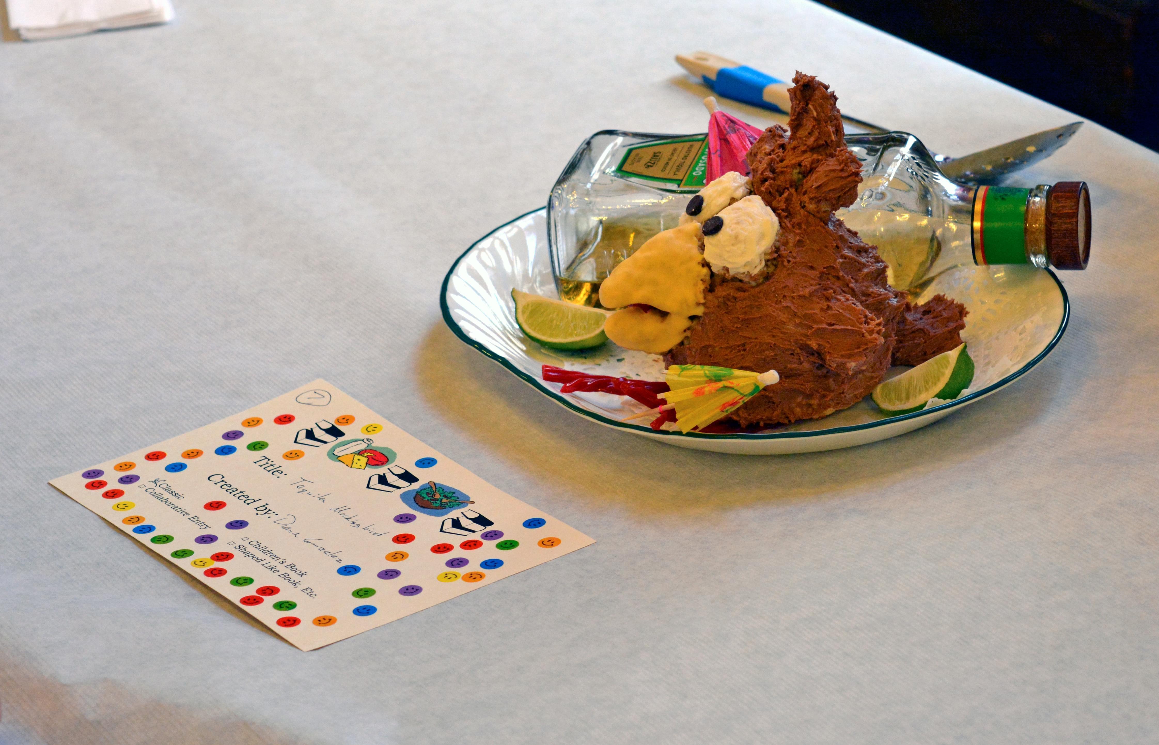 a cake called tequila mockingbird decorated to look like a drunk bird and a bottle of tequila