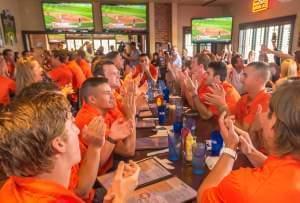 Members of the Illinois baseball team cheer as they learn about their No. 6 national seed in the NCAA Baseball Tournament at Billy Barooz in Champaign Monday.