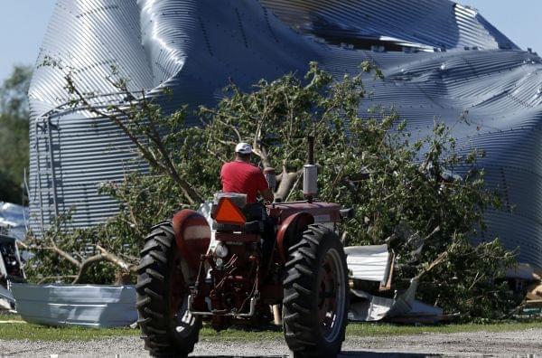 Bernie Burla drives a tractor past a damaged grain silo on his family farm Tuesday, June 23, 2015, in Coal City, Ill., after a tornado passed through the area Monday evening. 