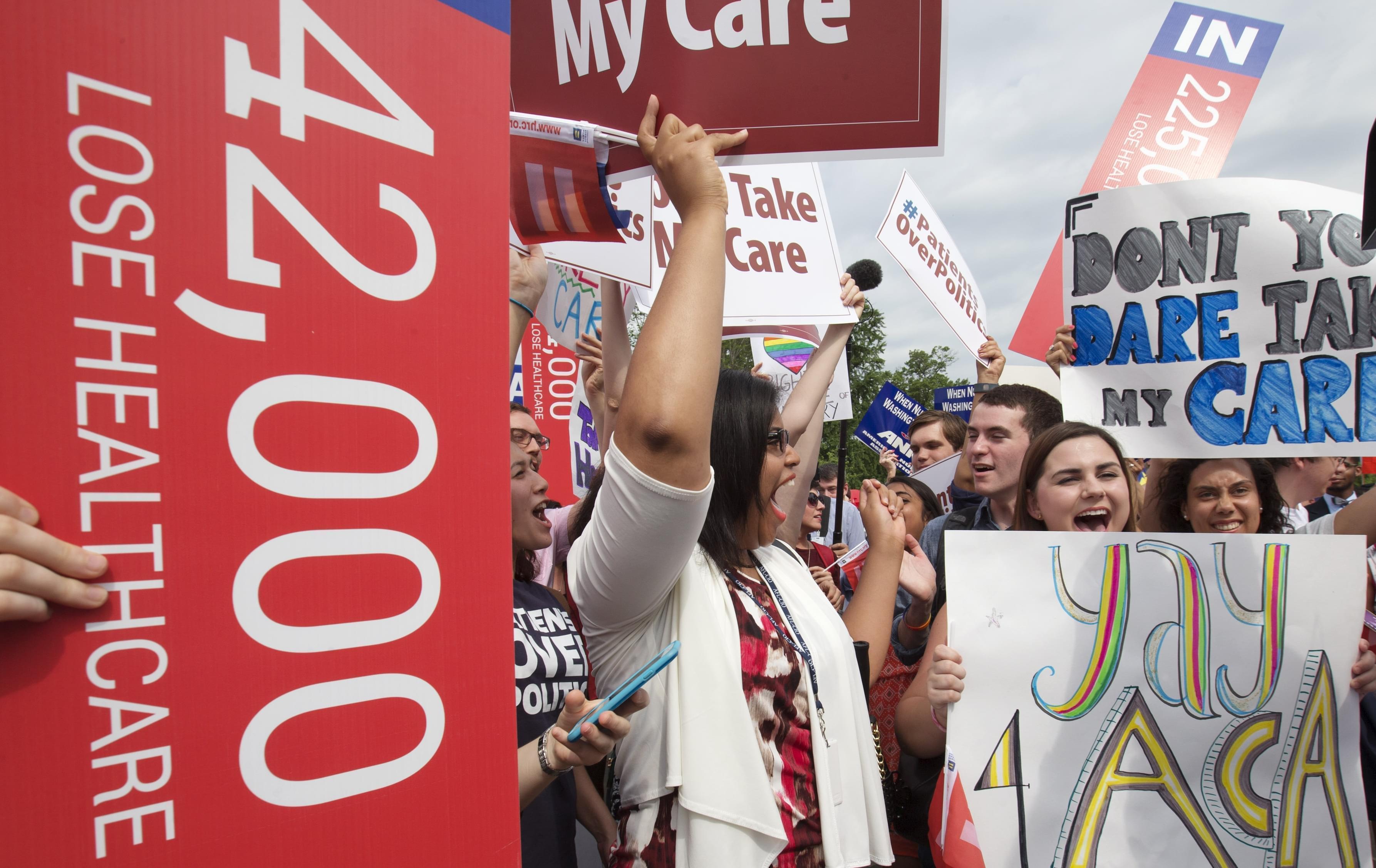 Jessica Ellis, right, with "yay 4 ACA" sign, and other supporters of the Affordable Care Act, react with cheers as the opinion for health care is reported outside of the Supreme Court in Washington Thursday.