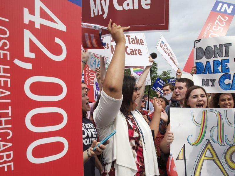 Jessica Ellis, right, with "yay 4 ACA" sign, and other supporters of the Affordable Care Act, react with cheers as the opinion for health care is reported outside of the Supreme Court in Washington Thursday. 