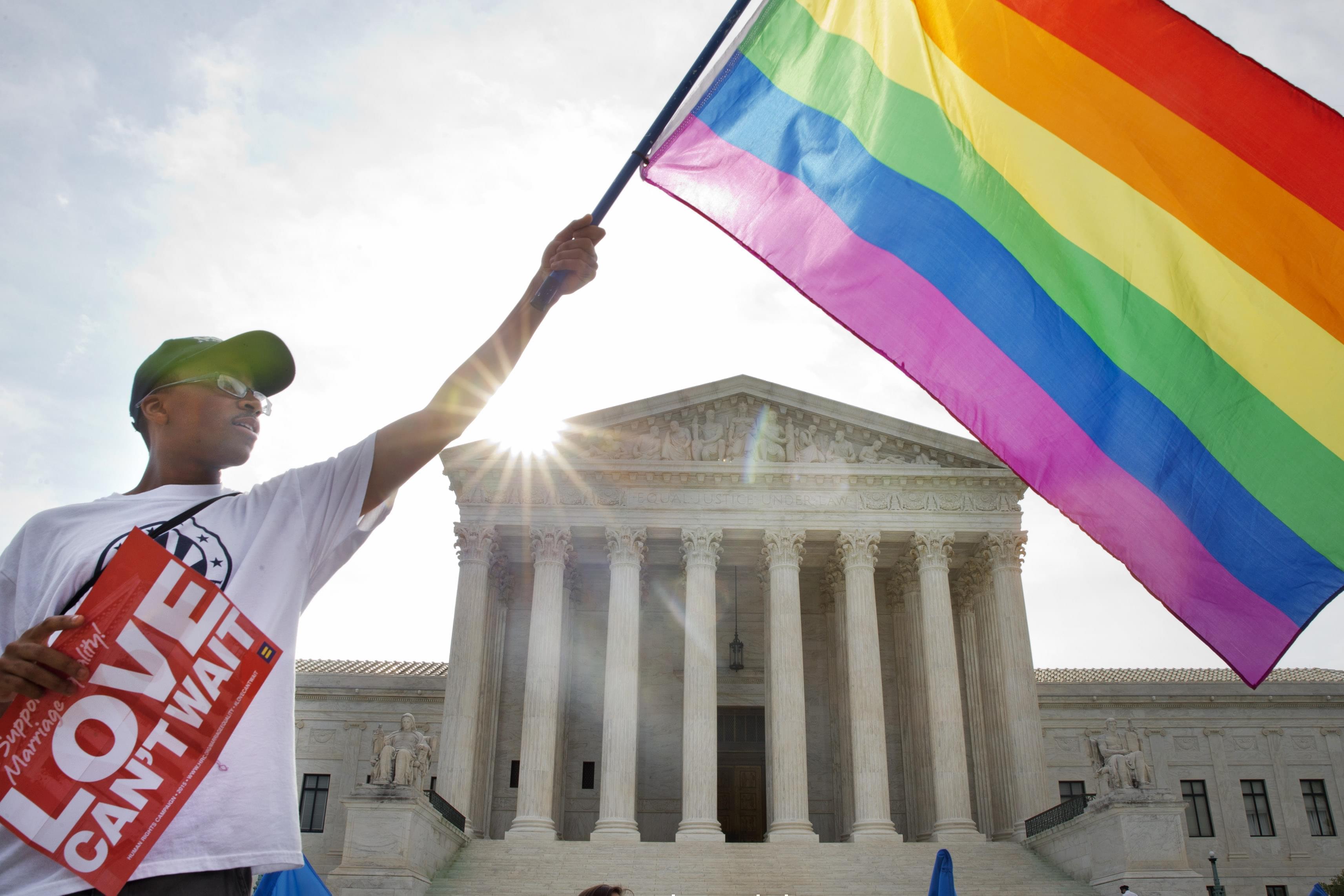Carlos McKnight of Washington, waves a flag in support of gay marriage outside of the Supreme Court in Washington Friday.