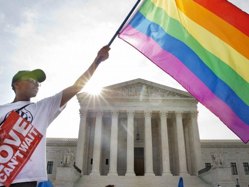 Carlos McKnight of Washington, waves a flag in support of gay marriage outside of the Supreme Court in Washington Friday.