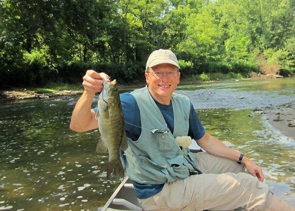Rob Kanter holds a smallmouth bass in a boat on the Salt Fork River