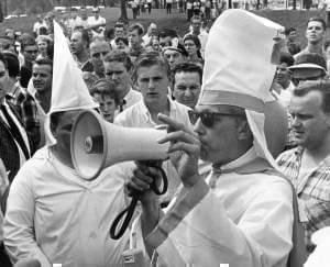 Man clad in Ku Klux Klan type robes uses bullhorn to address crowd in Marquette Park, Chicago on August 21, 1966 following rally staged by American Nazi Party. He was arrested for speaking without a permit and identified himself as Evan Lewis, 34, of