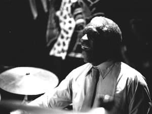 An African American man behind a drum set.