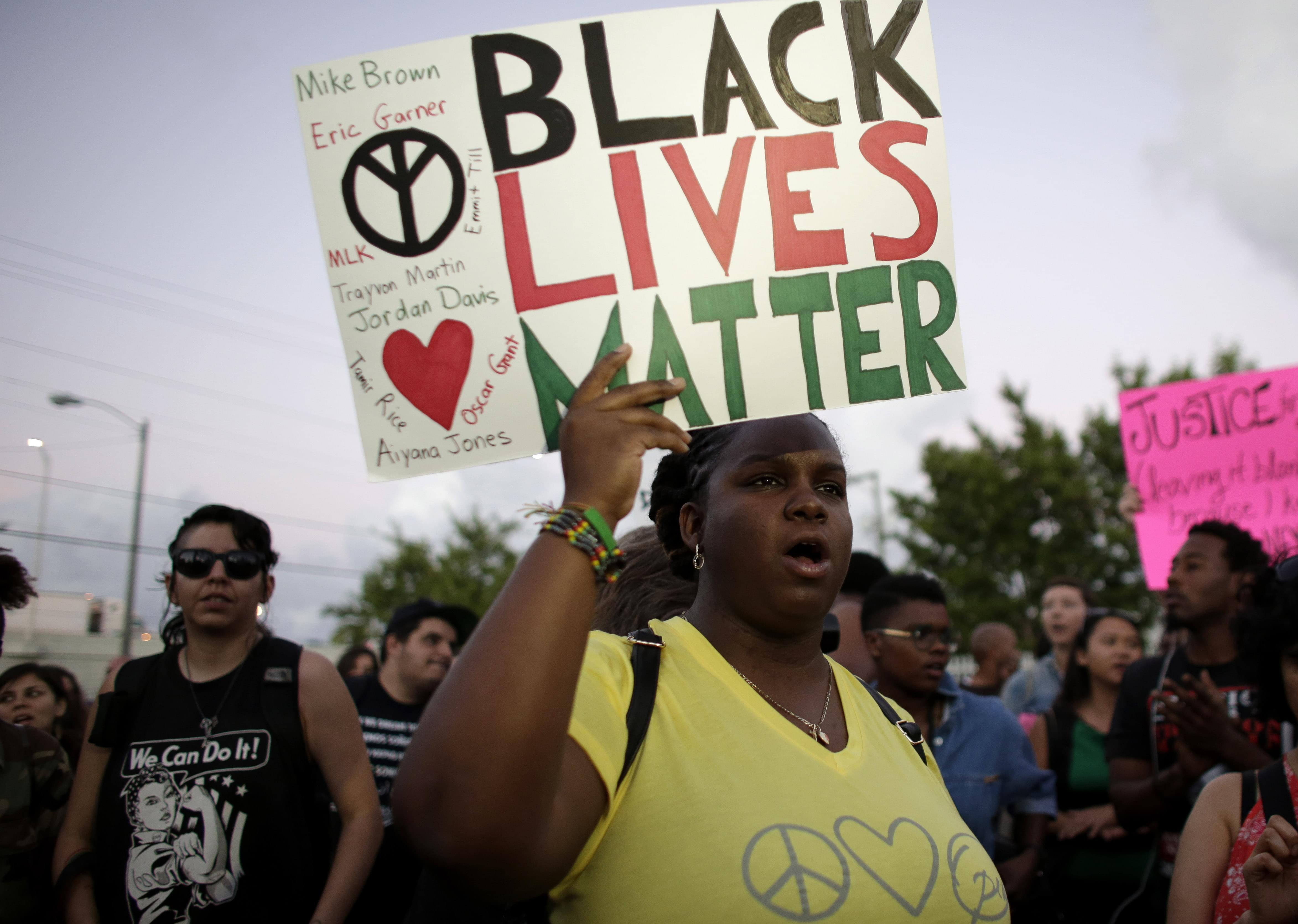 Desiree Griffiths, 31, of Miami, holds up a sign saying "Black Lives Matter", with the names of Michael Brown and Eric Garner, two black men recently killed by police, during a protest Friday, Dec. 5, 2014, in Miami. People are protesting n