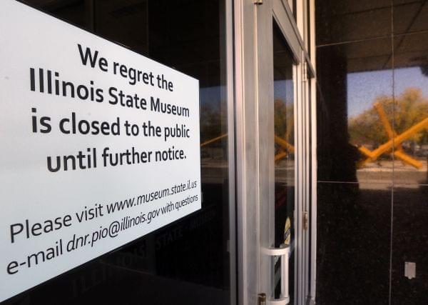 The reflection of a sculpture highlights the closing notice on the front door of the Illinois State Museum, Thursday, Oct. 1, 2015, in Springfield.