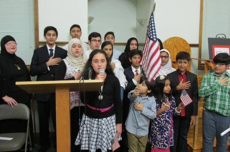 Muslim youth lead the pledge of allegiance and national anthem at the interfaith prayer vigil in Springfield