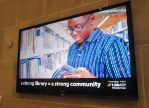 A monitor screen in the lobby of the Champaign Public Library displays an ad seeking donations for the Library Foundation.