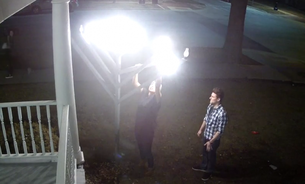 Screenshot of security video shows Ruby Fernandez-Rivera vandalizing the outdoor menorah at the Illini Chabad Center for Jewish Life, while a second person watches.