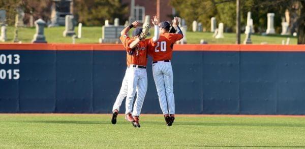 Three Illini baseball players jumping together in celebration after a win.
