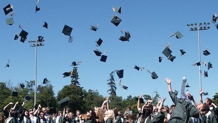At a college graduation ceremony, new graduates throw their caps into the air.