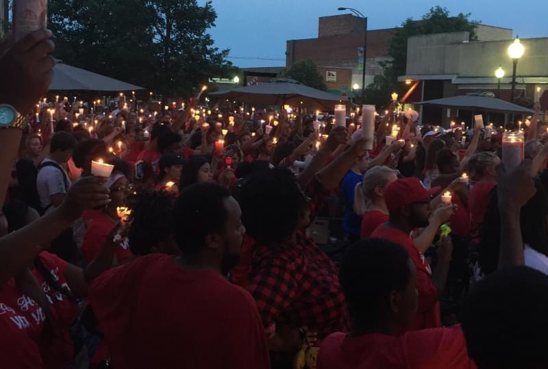 Hundreds of people raise up lit candles at a memorial vigil for Devon McClyde.