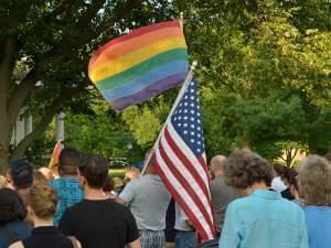 Two people hold an American flag and a LGBTQ Pride Flag at a Champaign, IL, Vigil for Orlando