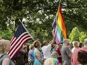 Men holding an American Flag and a Rainbow Pride flag together