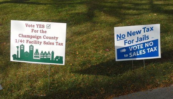 Two yard signs, one for and one against the Champaign County Facilities Sales Tax referendum.