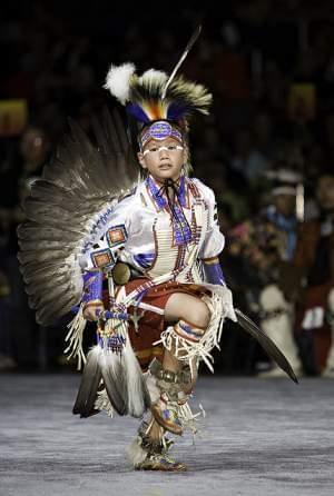 Elementary age Native American boy  in ceremonial dress dancing 