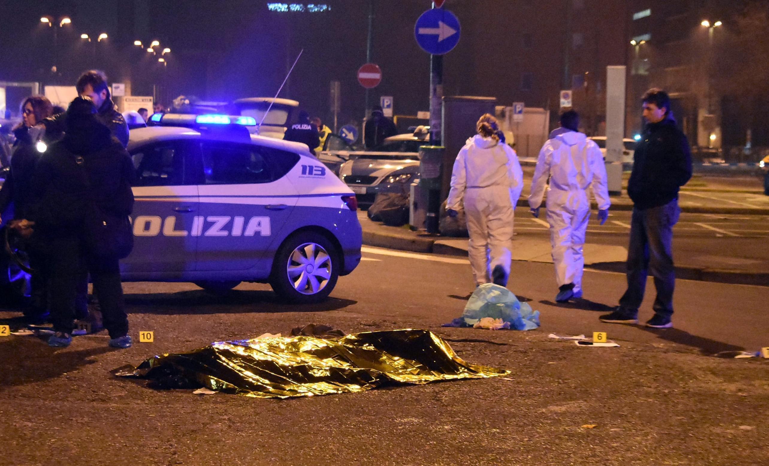 A body is covered with a thermic blanket after a shootout between police and a man near a train station in Milan's Sesto San Giovanni neighborhood,