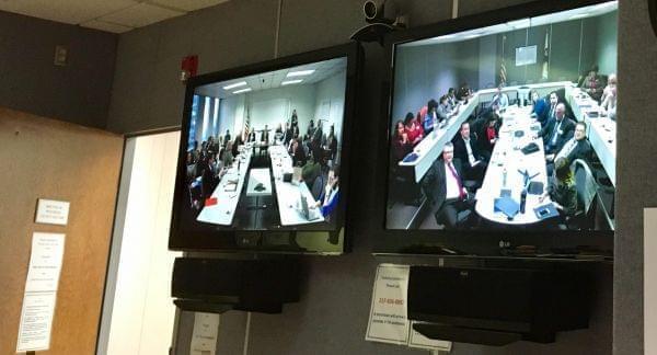 Video monitors show the Illinois Education Funding Reform Commission meets via speakerphone linking conference rooms in Springfield and Chicago. 