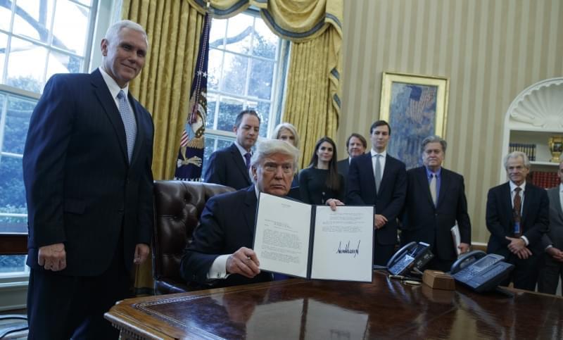 resident Donald Trump, accompanied by Vice President Mike Pence and staff, shows his signature on an executive order on the Keystone XL pipeline, Tuesday, Jan. 24, 2017, in the Oval Office of the White House in Washington.
