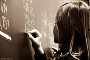 Young girl completing a math problem on a chalkboard