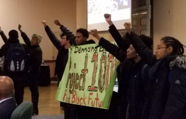 Members of the Black United Front unfurl a banner at Wednesday's University of Illinois trustees meeting. 