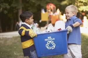 2 small children carrying  a recycling container 