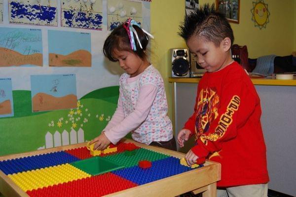 Preschool boy and girl playing at a Lego table in classroom