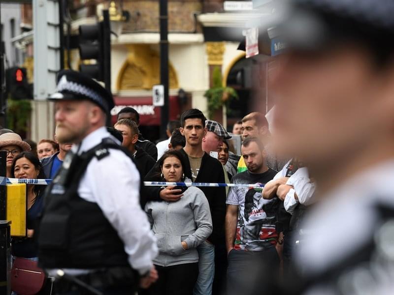 Londoners stand behind a cordon in the East Ham district on Sunday, following a police raid investigating Saturday's terror attacks in Central London.