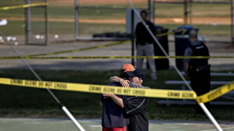 Two people embrace near the blocked-off crime scene in Alexandria, Va., where at least five people were wounded in a shooting during a congressional baseball practice Wednesday. The suspected gunman has died, officials say.