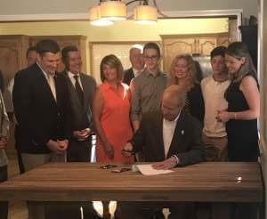 Governor Bruce Rauner signs 'Charlie's Law' at a home in Lombard on Tuesday as lawmakers from both parties look on.