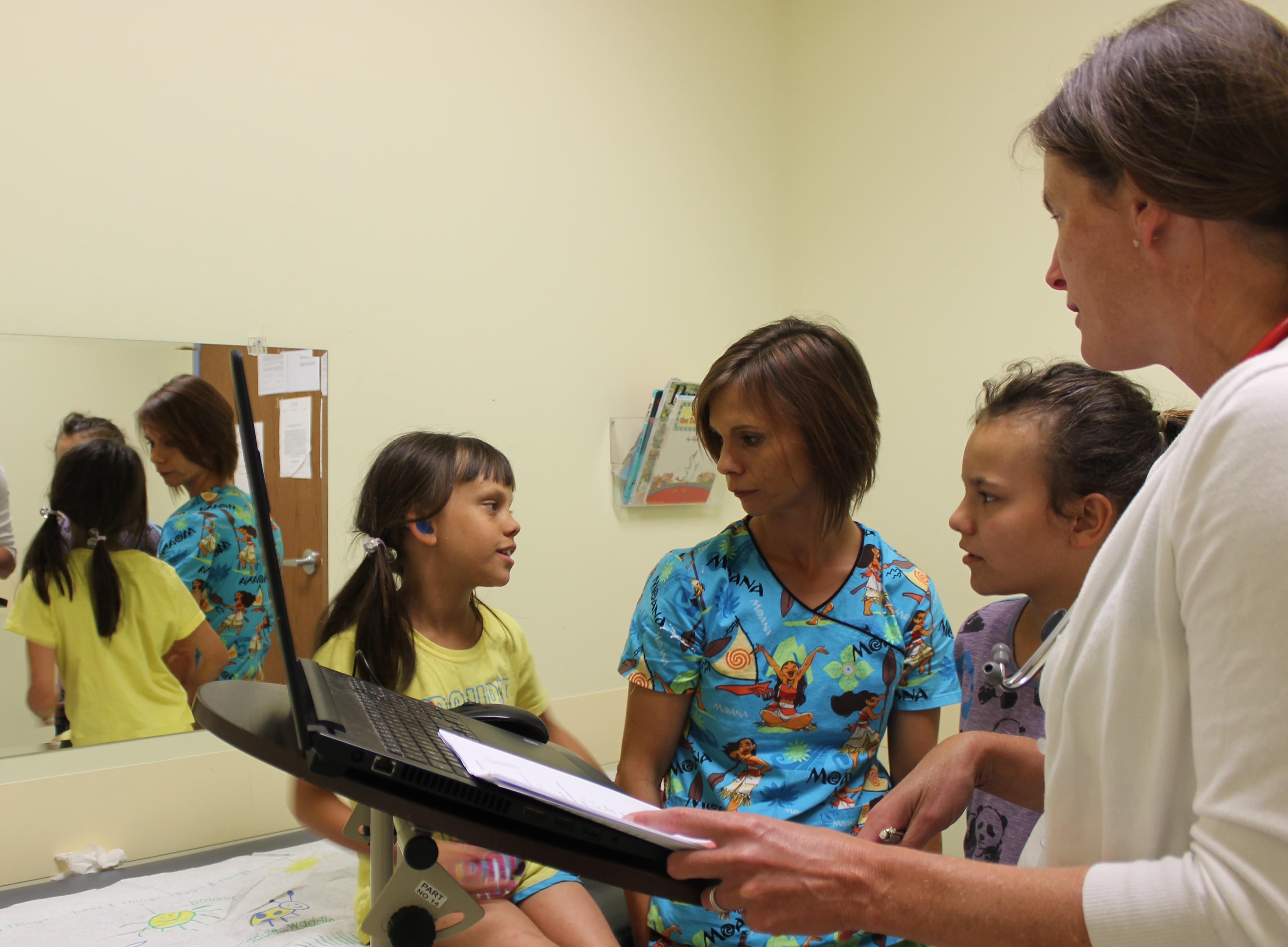 Dr. Kristin Stahl (far right) of Heartland Pediatrics meets with patient, Makayla (far left), who came in for a physical exam on July 26 along with her mother, Wendy Kelly, and older sister, Laney.
