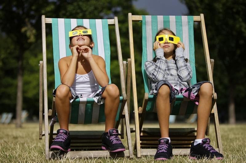 Neza Pintaric, 9 and sister Ula, 11, right, from Slovenia watch the partial eclipse of the sun through solar glasses in Hyde Park in central London, Friday August 1, 2008. 
